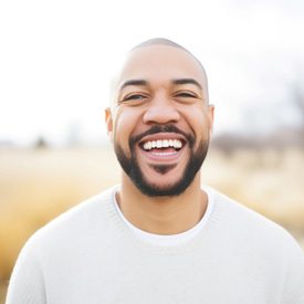 Man in white shirt smiling outside