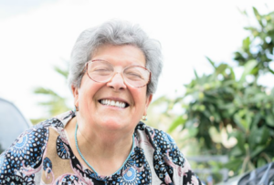 Senior woman smiling brightly outside with her dentures 